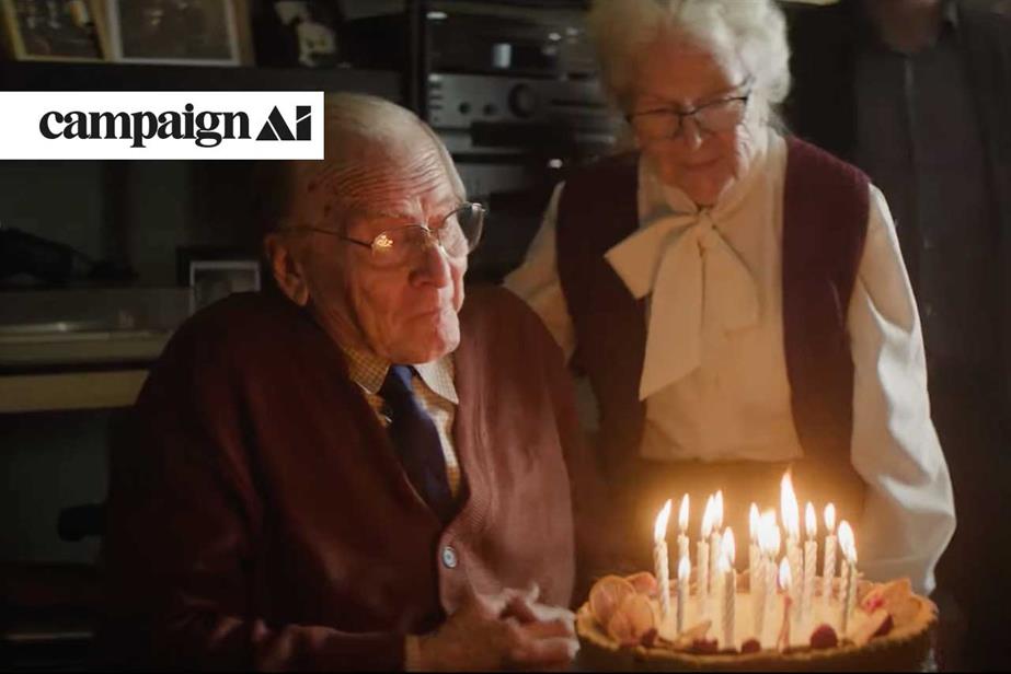 An elderly couple celebrating a birthday holding a cake with candles