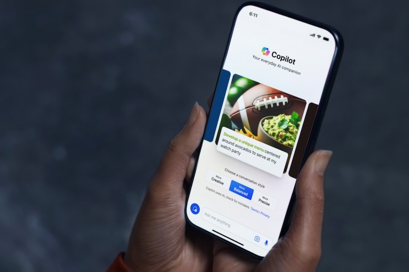 Hand holding smart phone displaying Copilot app
